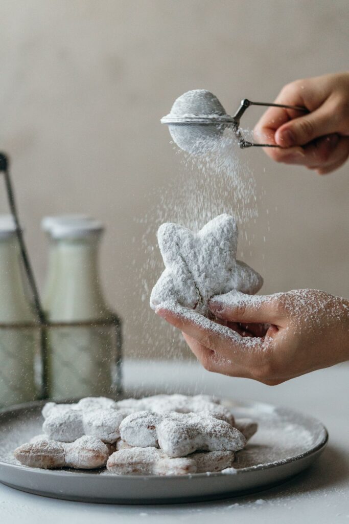 star shaped homemade beignets being dusted with powdered sugar