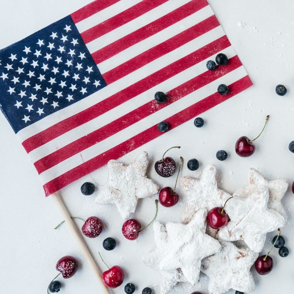 Star shaped homemade beignets styled with cherry's blueberries and an american flag for a festive 4th of july dessert