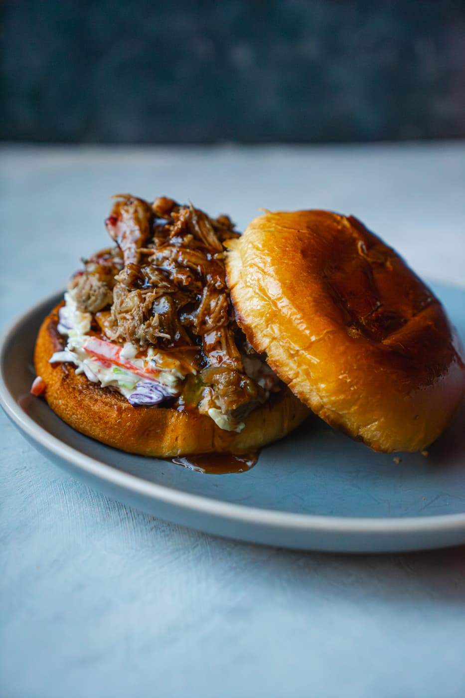 kelly-jean-TclQHtlkzRc-unsplash Juicy Pulled Pork inside a bun topped with coleslaw and smothered in BBQ sauce