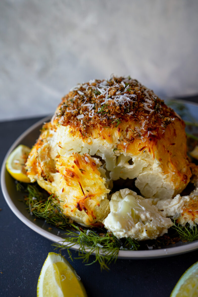 Cheesy Whole Roasted Cauliflower topped with dill and breadcrumbs